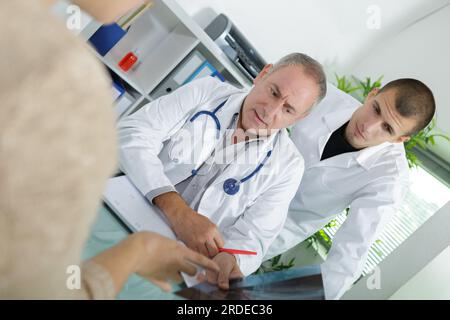 medico che discute i risultati dei raggi x con il medico junior che osserva il paziente Foto Stock