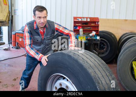 meccanico che spinge la ruota di camion pesante Foto Stock