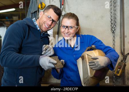 felice apprendista saldatrice al lavoro nello stabilimento Foto Stock