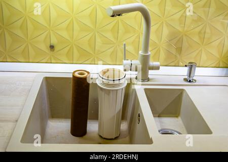 Fotografia a tema cartuccia filtro acqua per la casa su sfondo cucina, foto che consiste nell'installazione cartuccia filtro acqua a casa, sostituzione Foto Stock