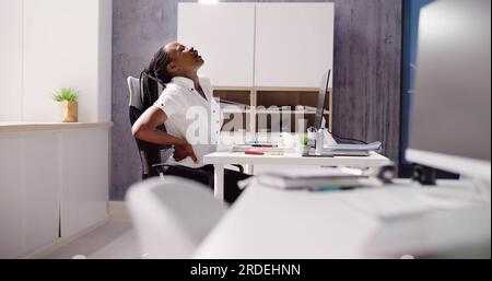 Donna afroamericana mal di schiena al lavoro a causa di una cattiva postura Foto Stock