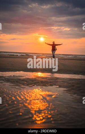 Turista in rosso al tramonto sulla spiaggia, Zandvoort, Paesi Bassi Foto Stock