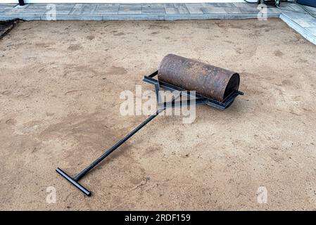 Sabbia gialla ondulata con un rullo d'acciaio per una piscina da giardino. Foto Stock