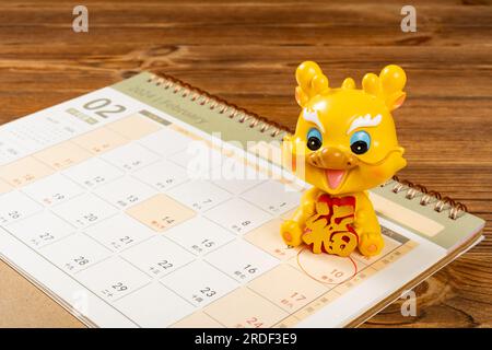Mascotte Year of Dragon con un calendario evidenziato sulla data del capodanno cinese la traduzione del cinese sulla mascotte è fortuna e la parola sulla Foto Stock