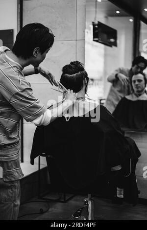 Un barbiere giapponese taglia i capelli di un cliente uomo in un barbiere. Foto Stock