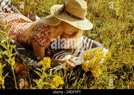 Young blonde woman in a straw hat with a book in the summer Stock Photo