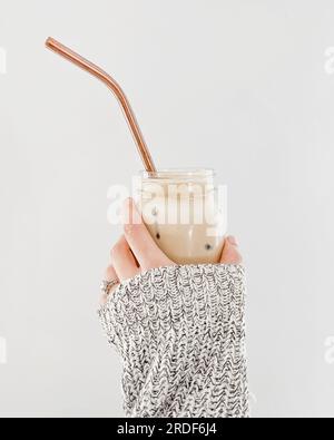 Mano che tiene il caffè freddo nel barattolo Mason con paglia Foto Stock