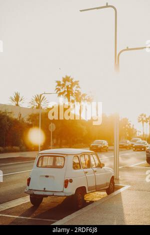 Un'auto bianca d'epoca è retroilluminata dal sole che tramonta in Marocco. Foto Stock