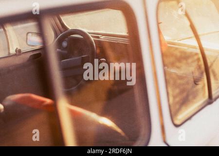 Un'auto bianca d'epoca è retroilluminata dal sole che tramonta in Marocco. Foto Stock