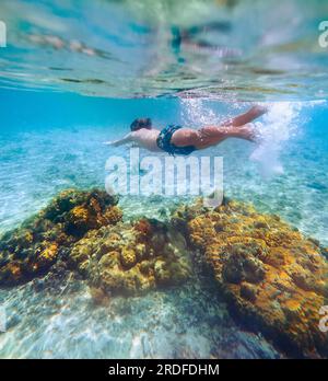 Immersioni ragazzi adolescenti snorkeling sopra le barriere coralline foto subacquea nella laguna turchese pulita sulla spiaggia di le Morne. Isola Mauritius. Viaggio esotico Foto Stock