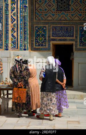 Donne alla bancarella di souvenir, Ulugh Beg Medressa, Registan, Samarcanda, Uzbekistan Foto Stock