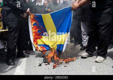 Teheran, Teheran, Iran. 21 luglio 2023. I manifestanti iraniani bruciano una bandiera svedese, durante una protesta per l'incendio di un Corano in Svezia, a Teheran, Iran, venerdì 21 luglio, 2023. Giovedì, un uomo che si è identificato nei media svedesi come rifugiato dall'Iraq ha bruciato un Corano per la seconda volta nel centro di Stoccolma. (Immagine di credito: © Sobhan Farajvan/Pacific Press via ZUMA Press Wire) SOLO USO EDITORIALE! Non per USO commerciale! Foto Stock