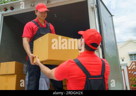 I lavoratori diligenti scaricano gli effetti personali da un camion, preparandosi diligentemente a spostarli in una nuova casa. Il loro efficiente lavoro di squadra garantisce un trasporto agevole Foto Stock