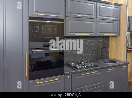 Forno a microonde nero e forno convenzionale costruito in cucina moderna elettrodomestici neri piano cucina in stile scuro Casa moderna Foto Stock