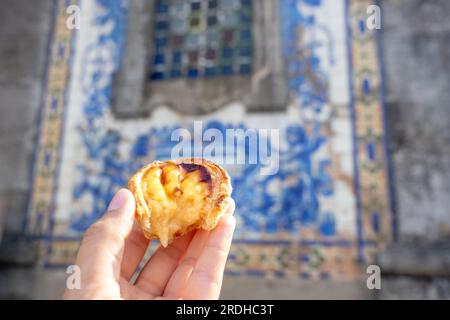 Tenendo pastel de nata a Porto Portogallo davanti a bellissime piastrelle blu azulejo bianche . Foto Stock