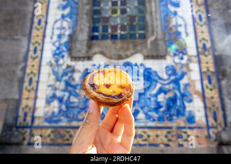 Tenendo pastel de nata a Porto Portogallo davanti a bellissime piastrelle blu azulejo bianche . Foto Stock