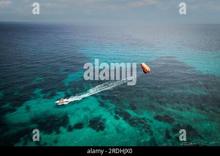 I turisti che amano il paracadutismo ascensionale sulla spiaggia sa coma di Maiorca, in Spagna, in una giornata estiva Foto Stock