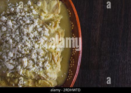 Enchiladas verde servito in un piatto di argilla su un tavolo di legno. Cucina tipica messicana. Foto Stock