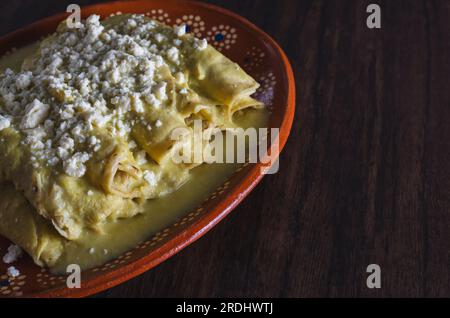 Enchiladas verde servito in un piatto di argilla su un tavolo di legno. Cucina tipica messicana. Foto Stock