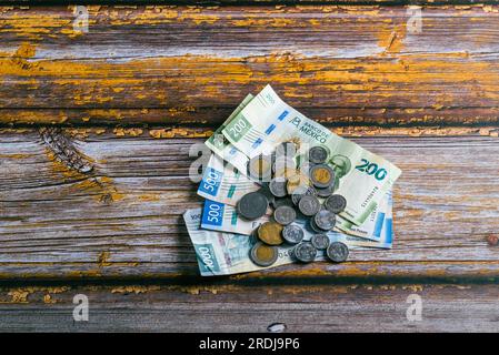 Pila di monete e banconote messicane su un tavolo di legno. Foto Stock