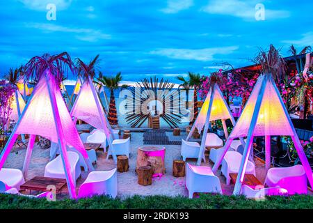 Espinho, Porto, Portogallo - 19 giugno 2023: Scena notturna sulla spiaggia con terrazza ristorante con sedie, tavoli e ombrelloni colorati decorativi a b Foto Stock