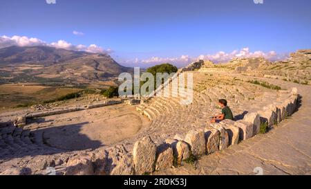 Luce notturna, anfiteatro romano, ragazzo seduto di lato, Segesta, sito antico, sito archeologico, dorico, Provincia di Trapani, Sicilia, Italia Foto Stock