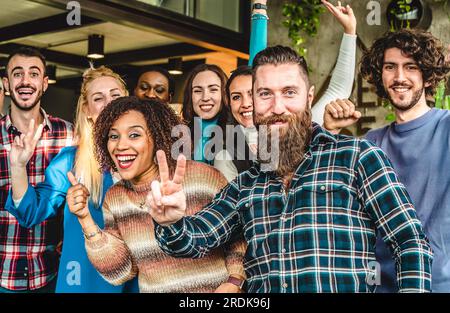 Studenti universitari multietnici e gioiosi o giovani imprenditori che guardano la fotocamera con gesti di vittoria per una foto di gruppo - concetto di raggiungimento degli obiettivi Foto Stock