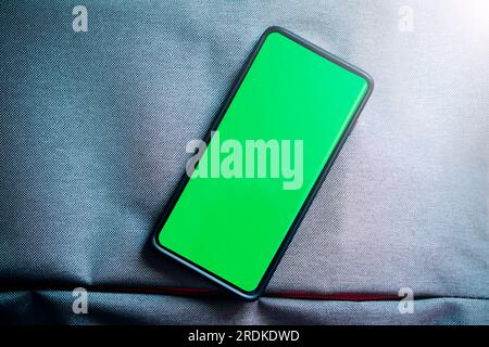 Foto flat lay dello schermo verde dello smartphone. Schermo del telefono Chroma Key in posizione verticale. Foto mockup con spazio per la copia. Internet delle cose. Foto Stock