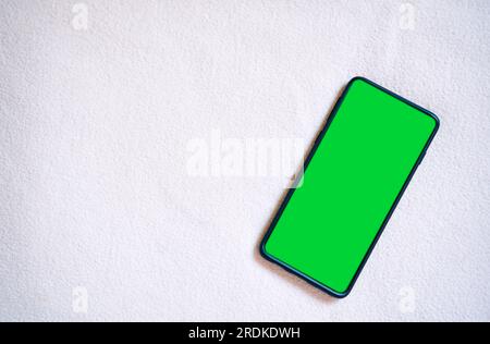 Foto flat lay dello schermo verde dello smartphone. Schermo del telefono Chroma Key in posizione verticale. Foto mockup con spazio per la copia. Internet delle cose. Foto Stock