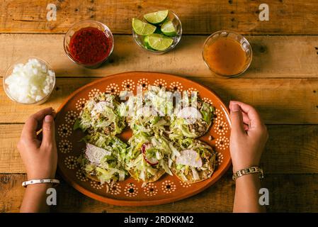 Mani di donna che preparano sopitos in stile Colima su un tavolo di legno. Tipico cibo messicano. Foto Stock