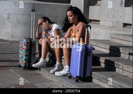 Madrid, Spagna. 21 luglio 2023. Due giovani turisti con le loro valigie si siedono in attesa in una calda giornata estiva durante un'ondata di caldo. Crediti: Marcos del Mazo/Alamy Live News Foto Stock