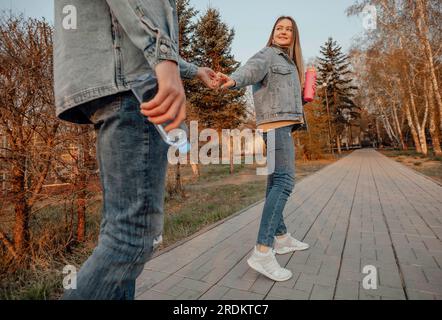 Una giovane coppia si diverte a fare una passeggiata rinfrescante nel parco con bottiglie d'acqua, godendosi l'idratazione e la serenità della natura Foto Stock