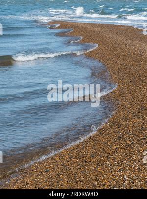 promontorio di shingle sulla spiaggia e sul mare con onde che si infrangono sulla riva creando motivi naturali lungo la linea di marea Foto Stock