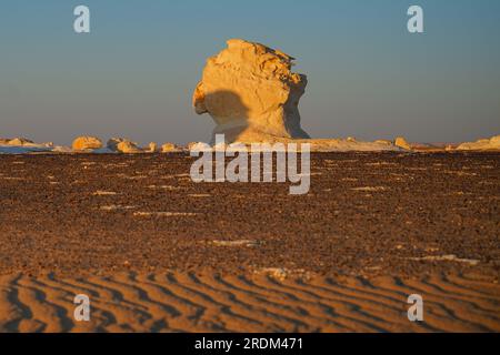 13 aprile 2023, Qsar El Farafra, Egitto: Il sole tramonta nel deserto bianco, Egitto. Dall'erosione dei vulcani e di una montagna di quarzo, alle rocce che intemprano e alle formazioni rocciose bianche di gesso, il deserto bianco e nero fa parte della depressione di Frarafra nel deserto del Sahara e si trova nella parte occidentale dell'Egitto. Il vasto deserto collega alle strade principali che si trovano vicino al confine libico-egiziano, dove è ora pesantemente armato di presenza militare. Il bizzarro paesaggio naturale che si innalza da un fondo oceanico milioni di anni fa è ora lasciato con formazioni calcaree carsiche che assomigliano alla superficie di o Foto Stock