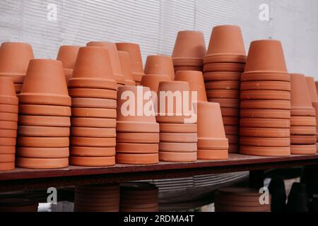 Vasi di fiori di terracotta impilati sugli scaffali al centro del giardino Foto Stock