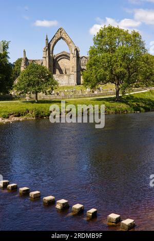 Sassi sul fiume Wharfe con le rovine dell'abbazia di Bolton sullo sfondo, Wharfedale e Yorkshire Dales National Park. Foto Stock