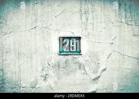 Number 29, twenty-nine, blue plate on a grungy white surface, split toned and slight vignette effect added. Foto Stock
