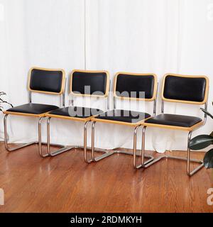 Set di sedie a sbalzo in vinile nero e cromo. Elegante arredamento moderno di metà secolo. Fotografia interna con lunghe tende bianche. Foto Stock