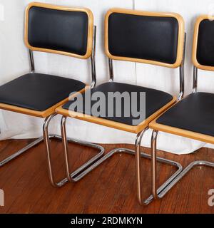 Set di sedie a sbalzo in vinile nero e cromo. Elegante arredamento moderno di metà secolo. Fotografia interna con lunghe tende bianche. Foto Stock