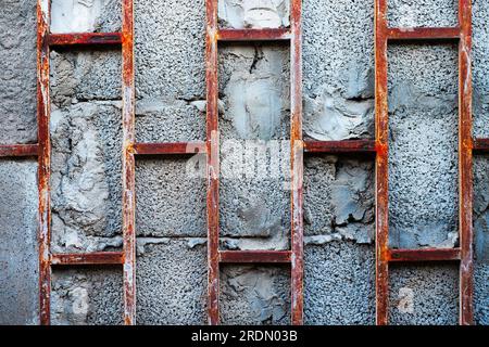 Barre arrugginite su blocchi di cemento grigio, un frammento astratto di vecchio edificio abbandonato. Foto Stock