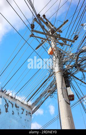 Palo di servizio con molti fili contro il cielo blu. Foto Stock