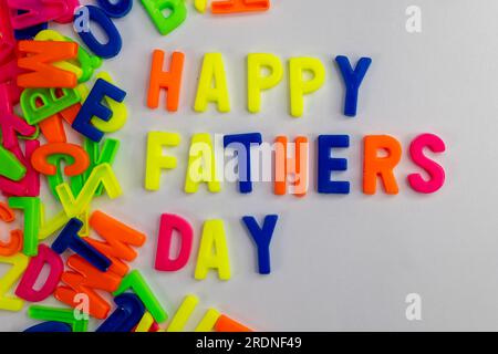 Questa immagine mostra le parole "Happy Fathers Day" realizzate con magneti colorati su uno sfondo semplice Foto Stock