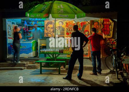 Pechino, CINA - persone all'esterno, quartiere vecchio - scena di strada - Hutong, piccolo negozio di alimentari sul marciapiede di Guanfang Hutong, area di Financial Street, notte, luci vecchi poster Foto Stock