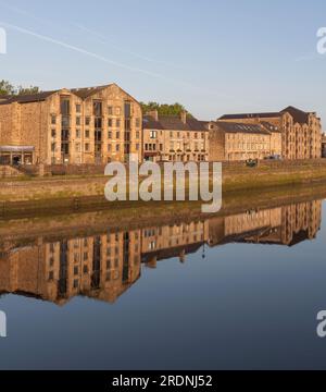 Saint Georges Quay (Lancaster, fiume Lune) in una mattinata immobile con gli edifici riflessi nel fiume Foto Stock