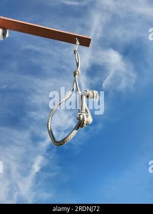 Il cappio della corda è sospeso su un mazzetto contro il cielo blu con le nuvole. Foto di alta qualità Foto Stock