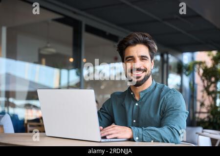 Felice giovane uomo d'affari latino che usa un computer portatile che lavora all'aperto, ritratto. Foto Stock