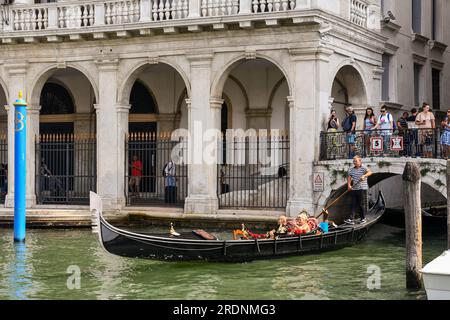 Giro in gondola sul Canal grande di fronte a Palazzo Dolfin Manin con i turisti sul Ponte Manin in estate, Venezia, Veneto, Italia Foto Stock