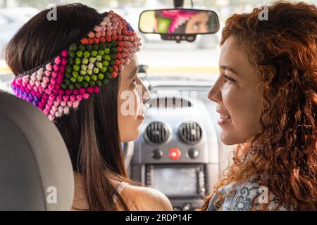 amore tra due giovani donne, che si guardano e sorridono, all'interno di un'auto, viaggiano come un'attività romantica e di coppia, stile di vita e trasporti Foto Stock