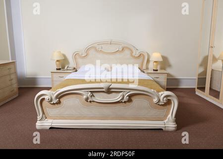 Elegante interno della camera da letto con comodo letto e lampade sui comodini Foto Stock