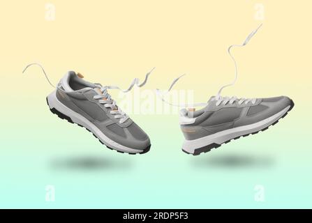 Un paio di eleganti sneaker in aria su sfondo sfumato di colore Foto Stock